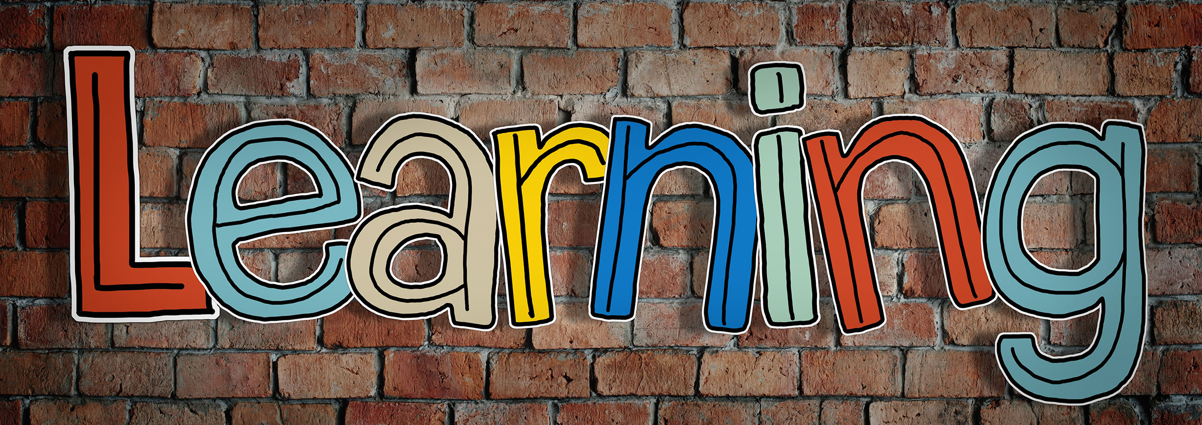 The word learning written on a brick wall in different colors.